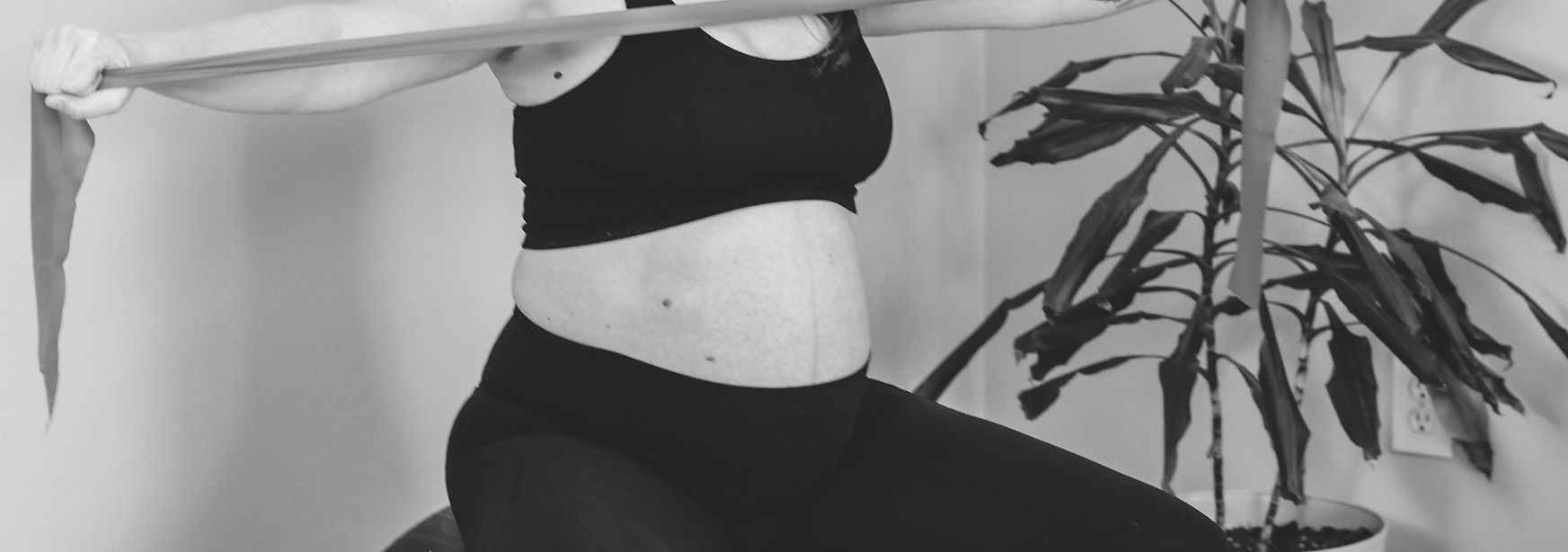 A pregnant woman performing a seated resistance band exercise during pelvic health physical therapy